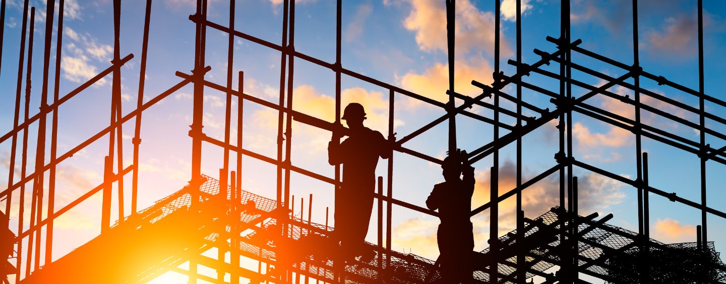 Silhouette of workers and a construction site as the sun sets