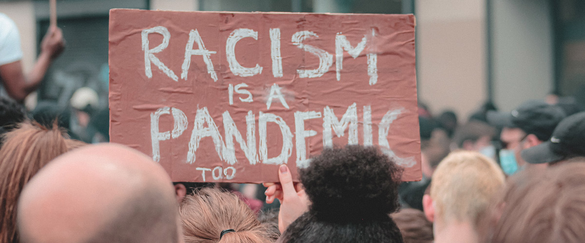 Protest sign says "Racism is a Pandemic"