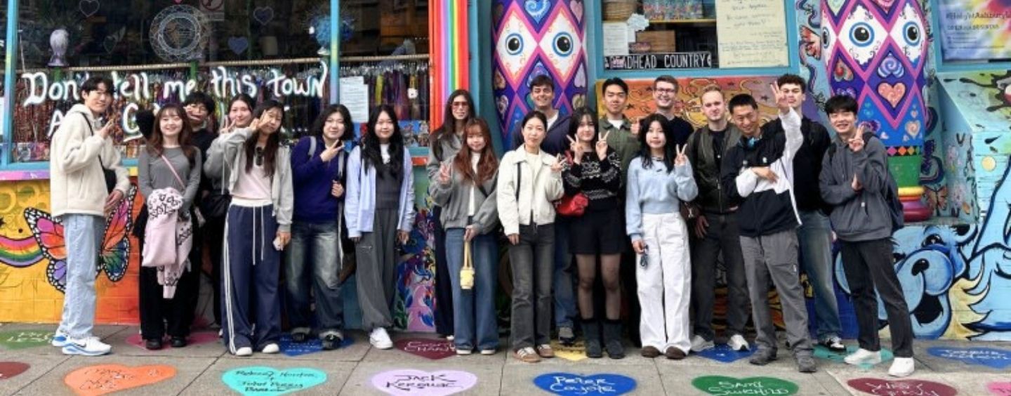 International students on a colorful sidewalk in front of a building with colorful murals