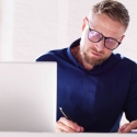 Professional man studying online and taking notes