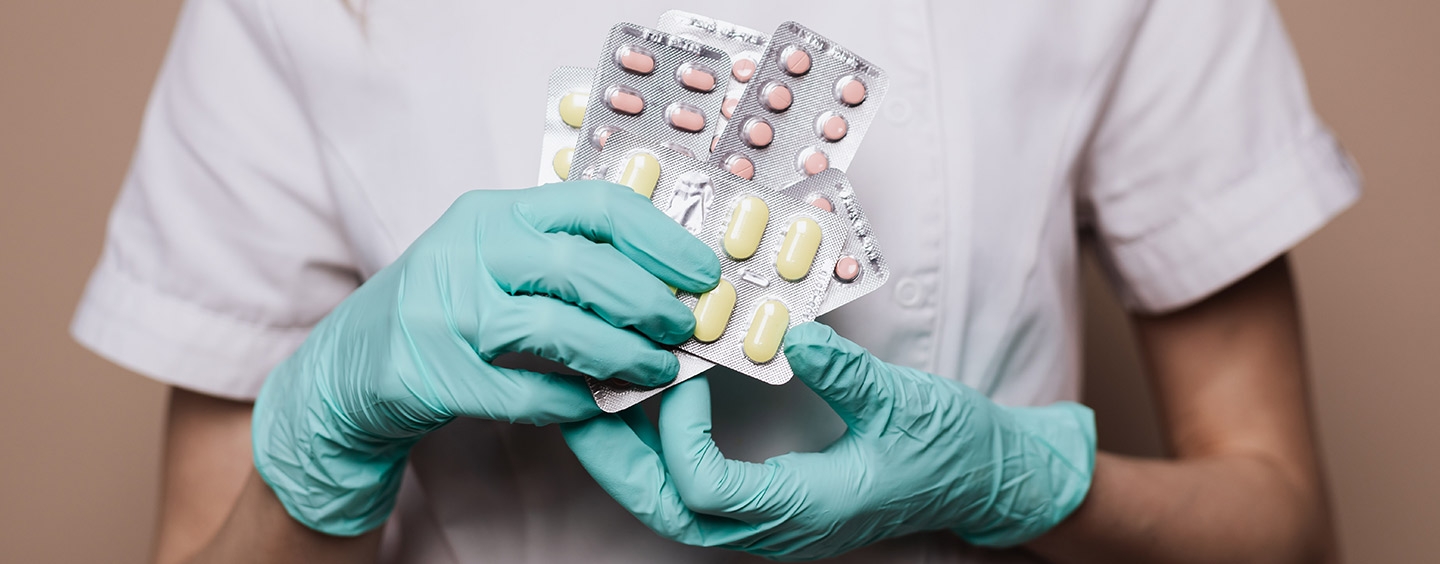 Pharmacy tech wearing gloves while holding pills