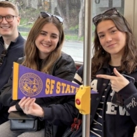 International students on Muni holding an SFSU pennant