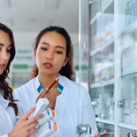 Two pharmacists read medication bottle