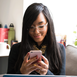 Mobile app developer smiles while looking at her pink smart phone