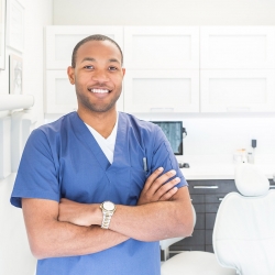 Dental assistant in scrubs in front of a dental chair