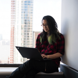 Network administrator sits in a window and works on her laptop