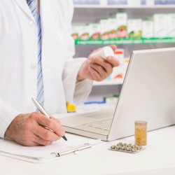 Pharmacist writing and using a laptop